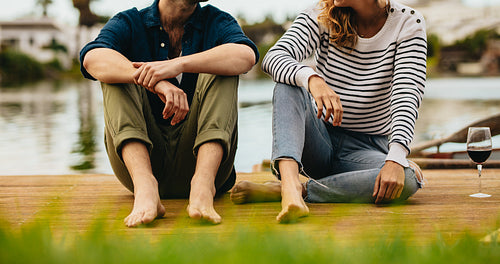 Couple on date sitting near a lake with drinks