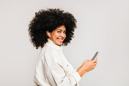 Happy young woman smiling at the camera while listening to music