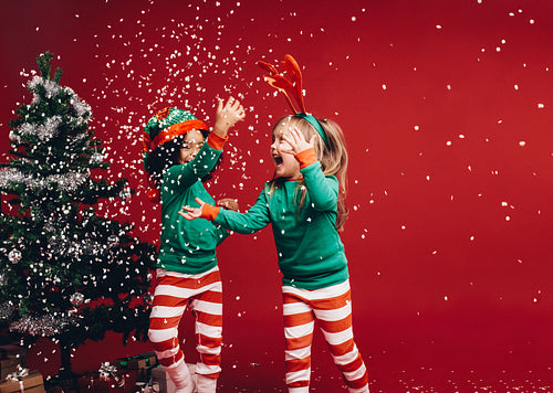 Little girls playing with the artificial snow flakes