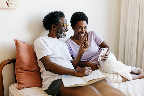 A romantic moment of with technology: Couple relaxing and using a phone in bed