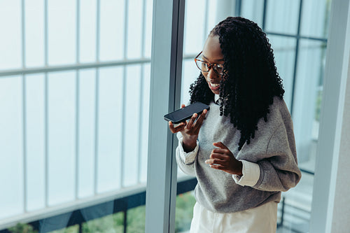 Confident female professional using phone to make a business call in modern office setting