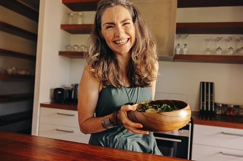 Healthy senior woman smiling happily while holding a buddha bowl