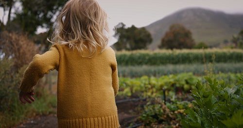 Adorable little girl running towards her brother on a farm
