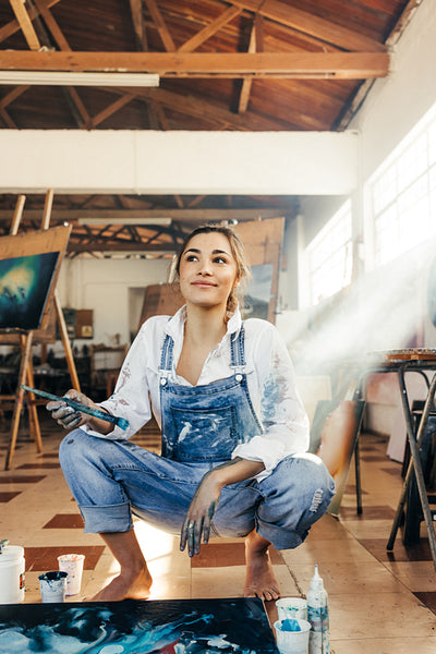 Pensive young painter squatting on the floor