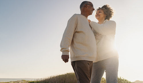 Happy senior couple standing on a foot bridge at the beach