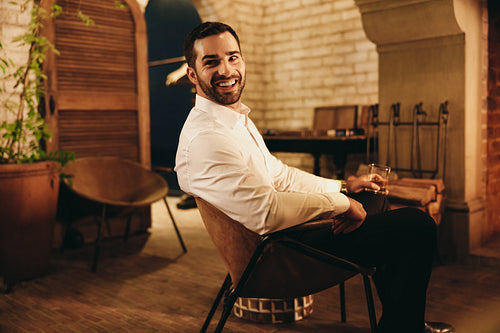Luxurious young man smiling while sitting alone in a hotel