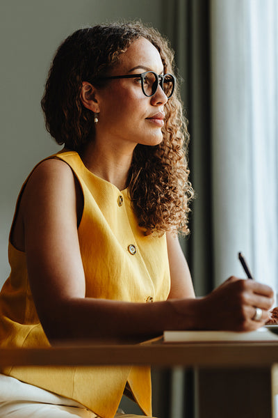 Thoughtful businesswoman journaling at her desk