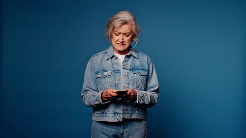 Confused senior woman looking at smartphone, trouble with technology, frustration