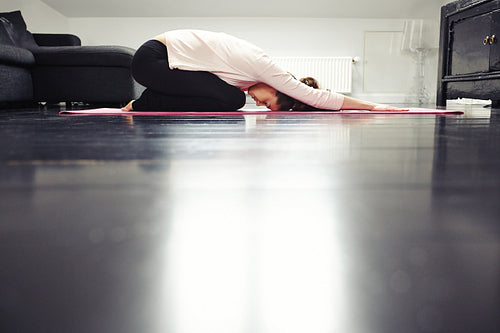 Fit young lady practicing yoga at home