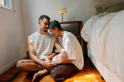 Happy couple sitting on bedroom floor sharing intimate moment