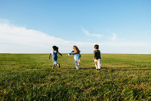 Children running freely in a sunny open field