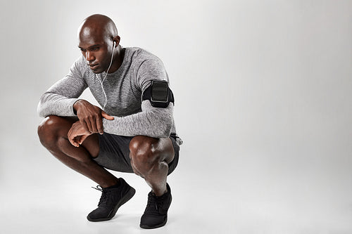 African male model crouching on grey background