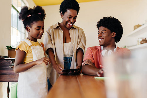 Happy family bonding over technology at home: Mother engages with kids using tablet