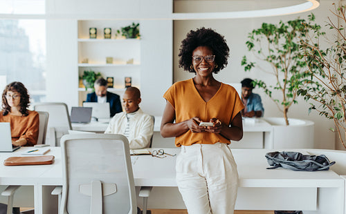 Successful afro-haired woman in modern office using smartphone