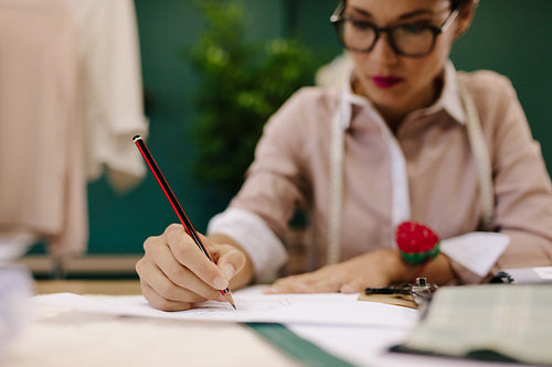 Woman tailor making dress design sketches