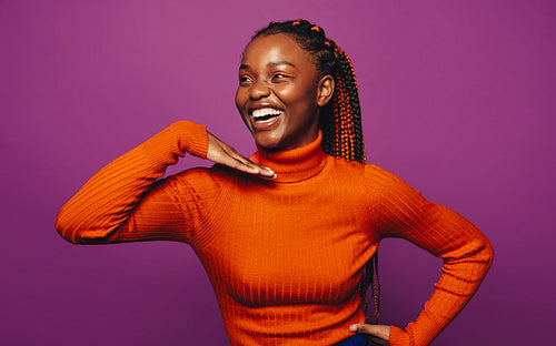 Confident and stylish gen z woman with two-tone braids standing on fun purple background