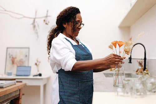 Small business owner arranging dry flowers in her floral shop