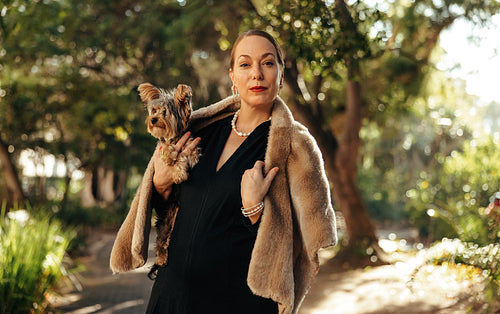 Luxurious woman looking at the camera while holding her puppy