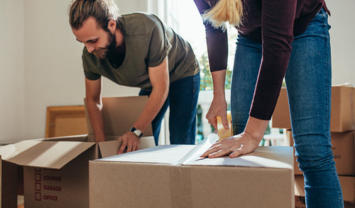 Couple working together in packing their household items in boxes