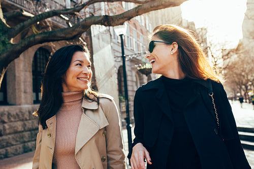 Female friends on walking down the street and smiling 