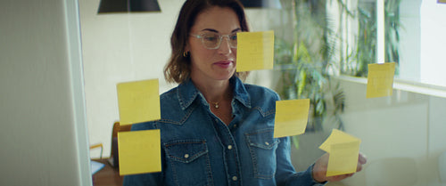 Businesswoman organizing ideas on sticky notes in a modern office