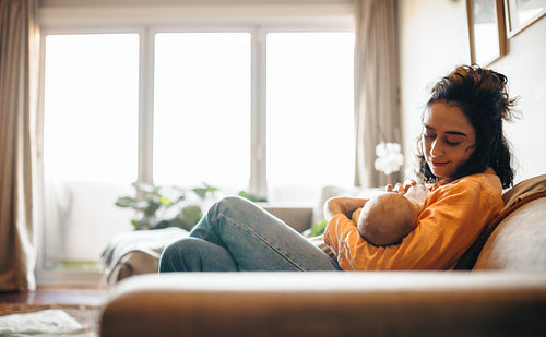 Mother nursing baby on couch at home