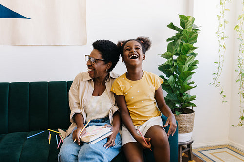Girl and her mother enjoying drawing with colour pencils at home