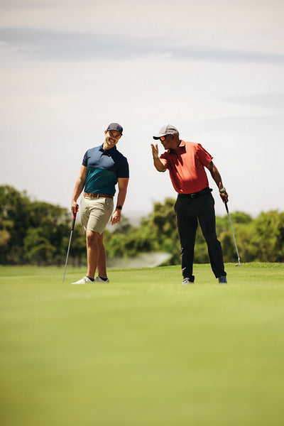 Two men strategizing on the golf course, discussing game tactics and wearing golfing attire