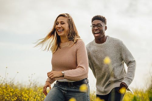 Couple playing and running through a meadow