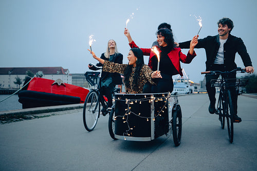 Friends riding bikes with sparklers in festive pre New Year’s celebration