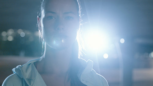 Urban female runner standing under bridge at night