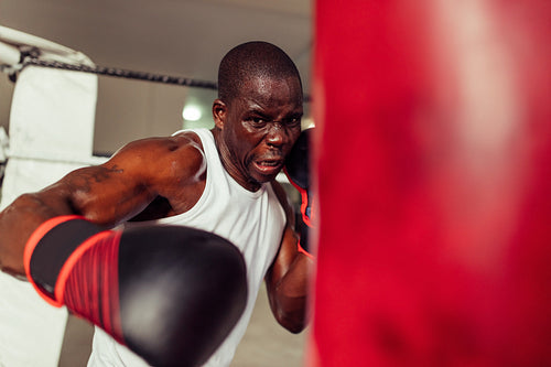 Young fighter swinging a gloved fist at a punching bag