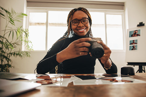 Female photographer holding a dslr camera in her home office