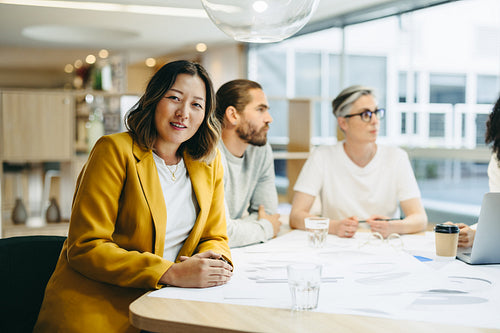 Cheerful businesswoman sitting in a meeting with her colleagues