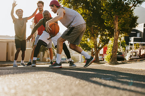 Men playing basketball on street