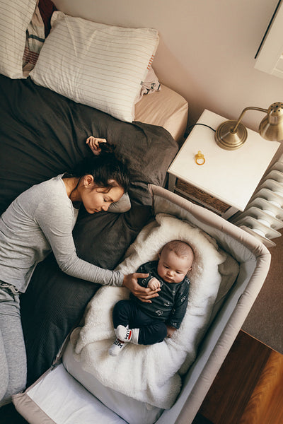 Mother and baby sleeping on bed in bedroom