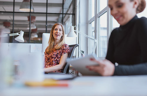 Young woman having friendly chat with her colleague