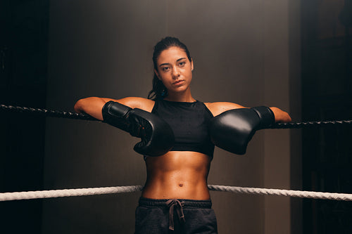 Confident boxer leaning against the ropes of a boxing ring