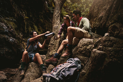 Friends taking coffee break while hiking in rocky mountain
