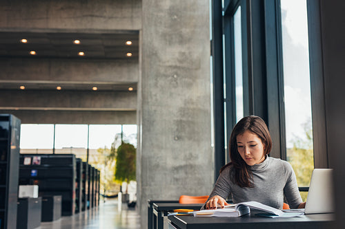 Female student doing assignments in library