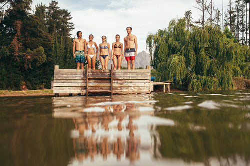 Young friends standing on jetty at the lake