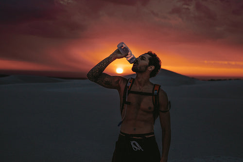 Athlete drinking water during workout in desert