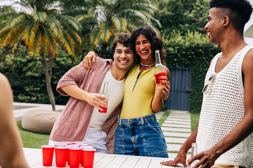 Beers and friends playing beer pong at a sunny backyard