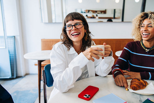 Friends laughing over coffee in cozy cafe