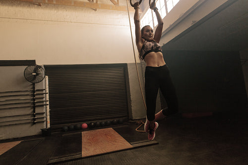 Woman exercising with dip rings at gym