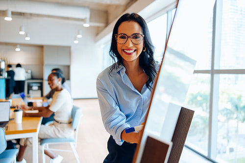 Smiling professional presenting ideas on a whiteboard in a bright office setting