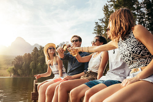 Young people toasting beers on a jetty