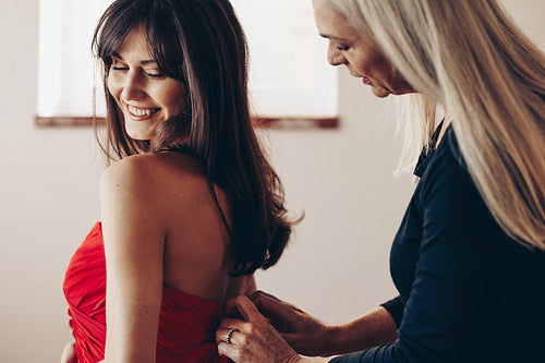 Mother helping her daughter in wearing a dress