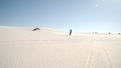 Motorbiker doing a wheelie while riding on sand dunes