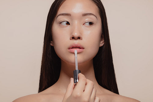 Woman applying transparent lip gloss